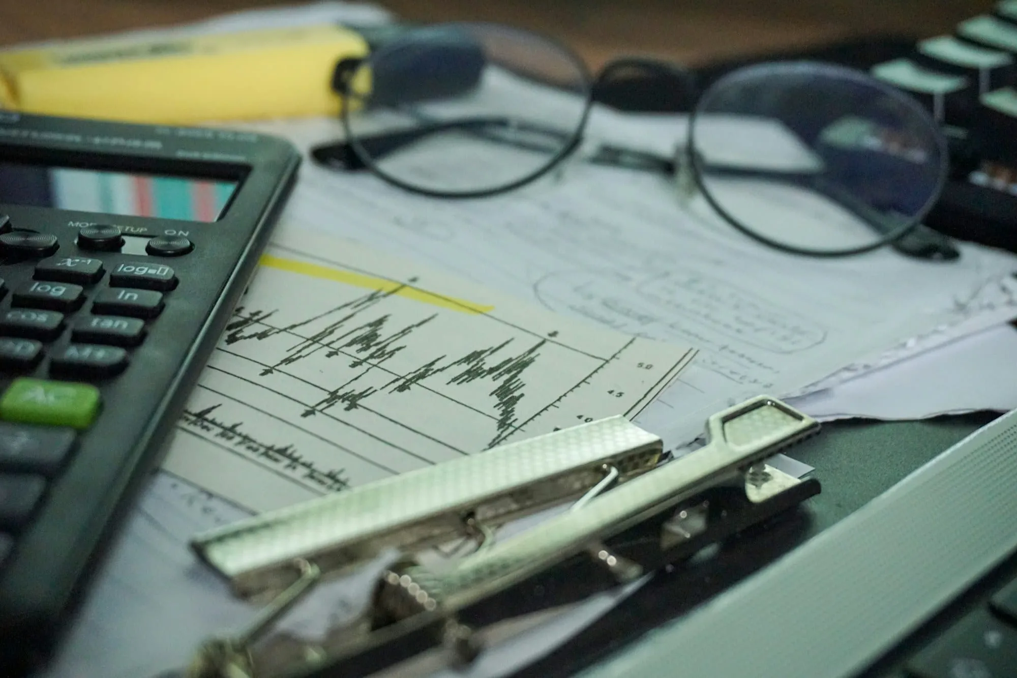Calculadora, gráficos impresos y gafas sobre una mesa de contabilidad