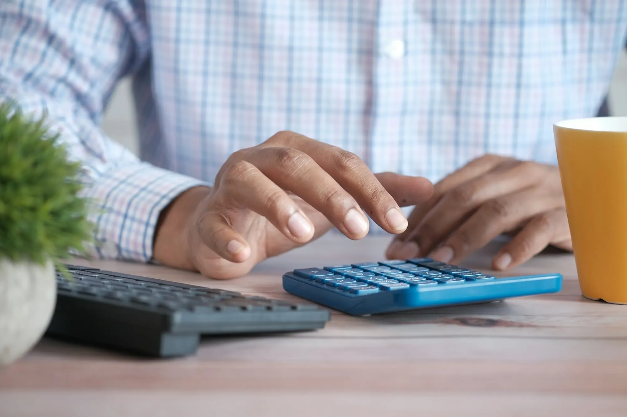Manos usando una calculadora en una mesa de oficina con un café