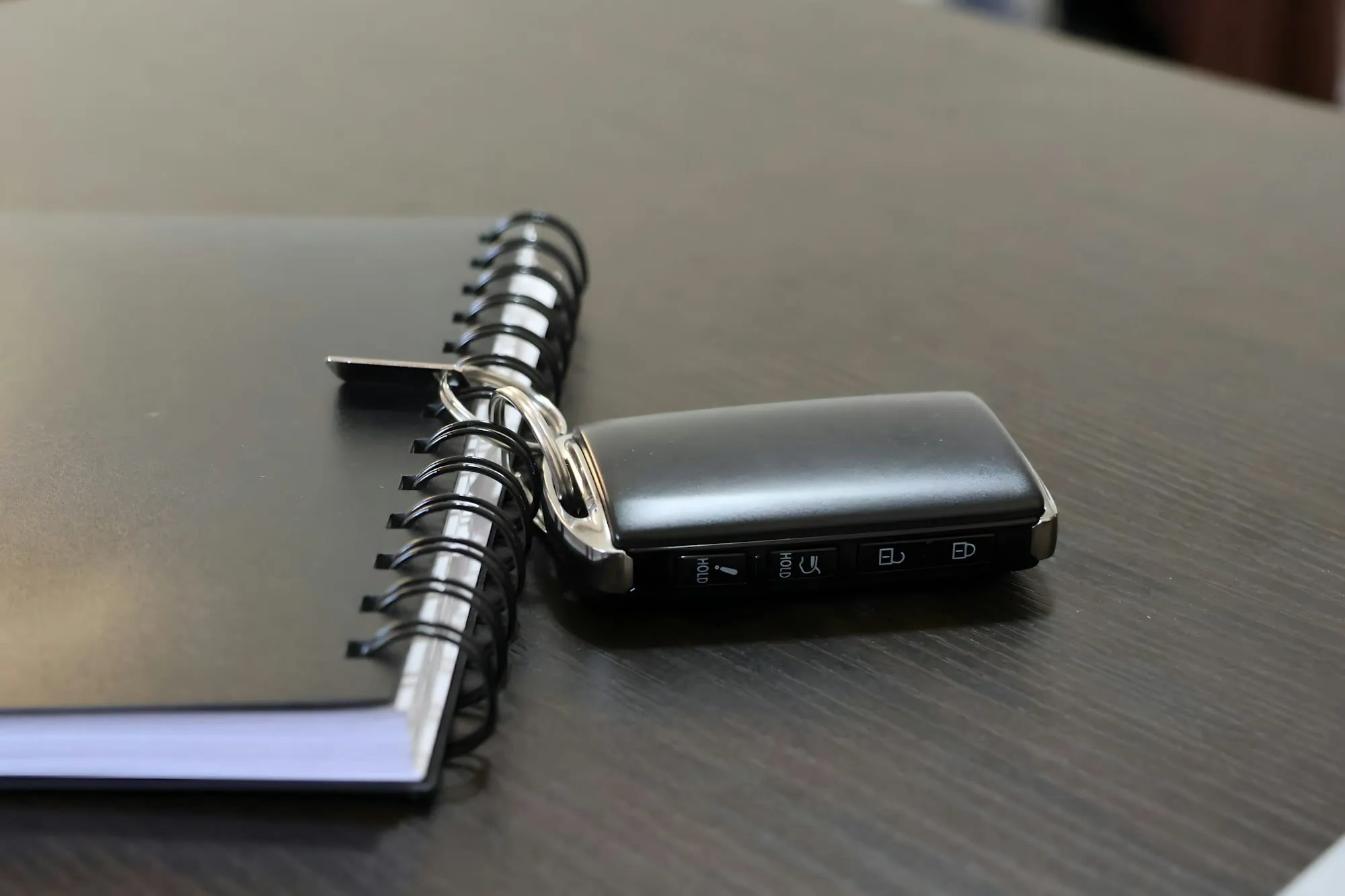 Llave de un coche junto a una agenda con las cuentas de la compra