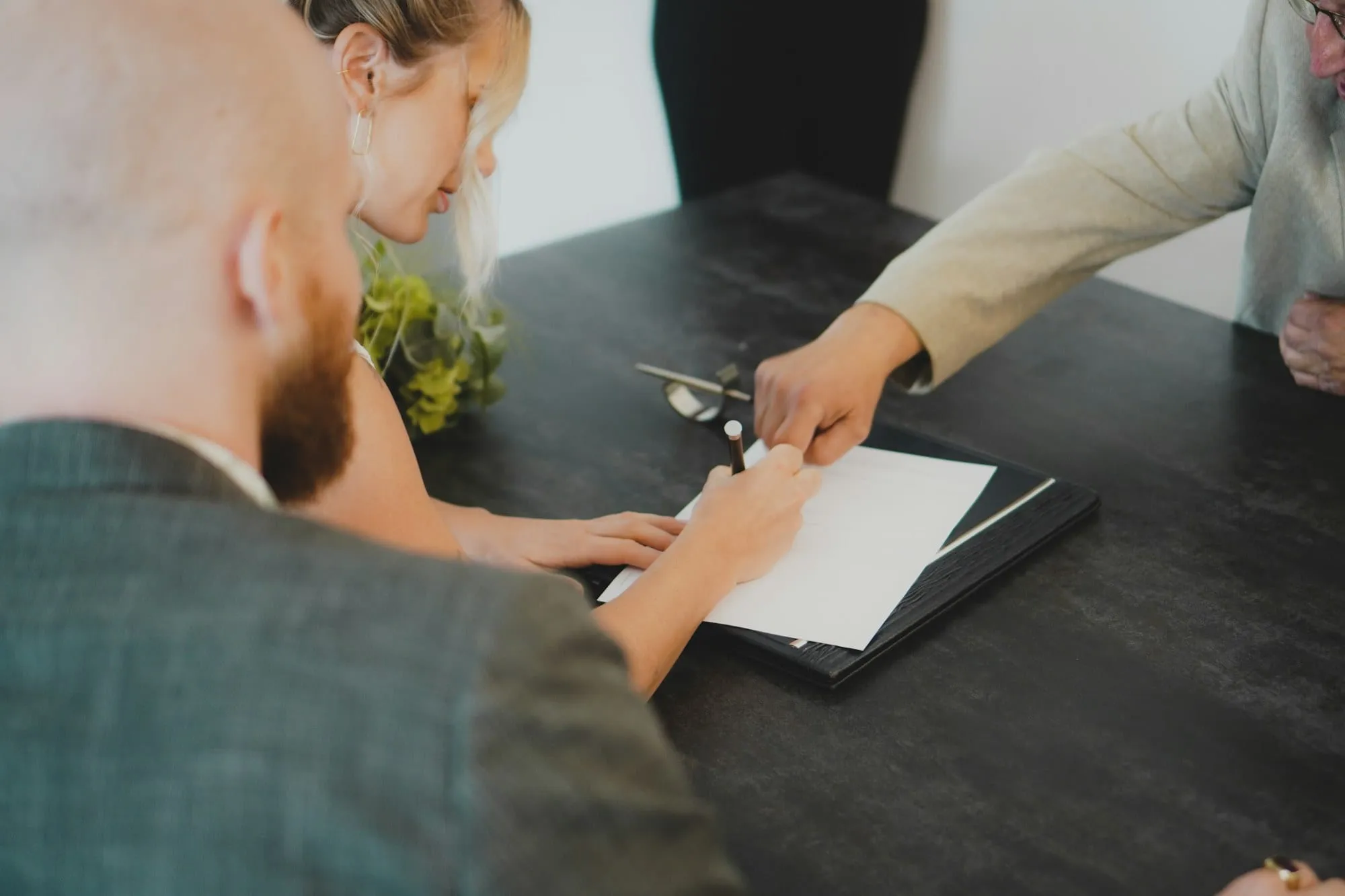 Dos personas firmando un contrato sobre una mesa